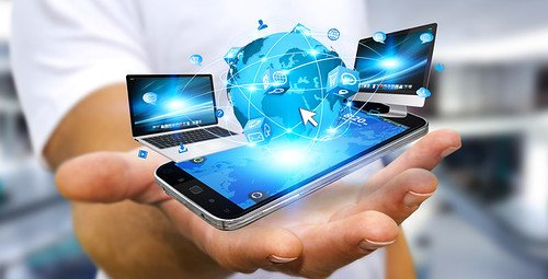 Mano sosteniendo un teléfono con iconos de laptop, monitor y globo terráqueo conectados sobre la pantalla
