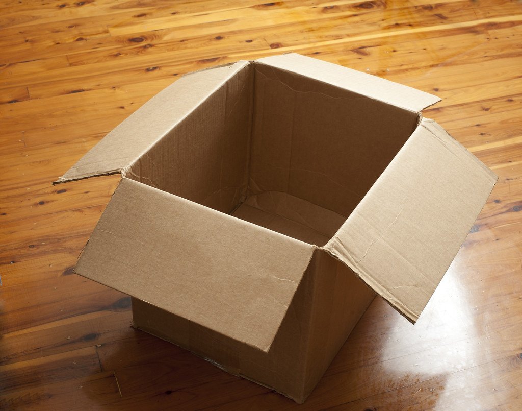 Caja de cartón abierta y vacía sobre un piso de madera